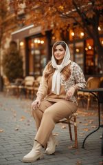 ست بافت زنانه کرم و نسکافه‌ای با طرح گلدار روی پلیور، ست شده با شلوار بافت و بوت روشن در کافه پاییزی