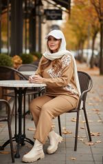 ست بافت زنانه نسکافه‌ای با طرح گلدار روی پلیور، ست شده با شلوار بافت و بوت روشن در استایل پاییزی کژوال