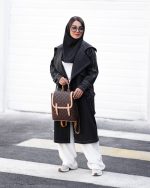 بارونی زنانه بلند دمسه دوزی مشکی کمربنددار فلاپ پشت استایل شهری روی ست روشن نمای تمام قد