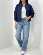 بامبر زنانه سرمه ای فیت آزاد یقه کشی روی تاپ سفید با شلوار جین گشاد و کتانی سفید نمای تمام قد